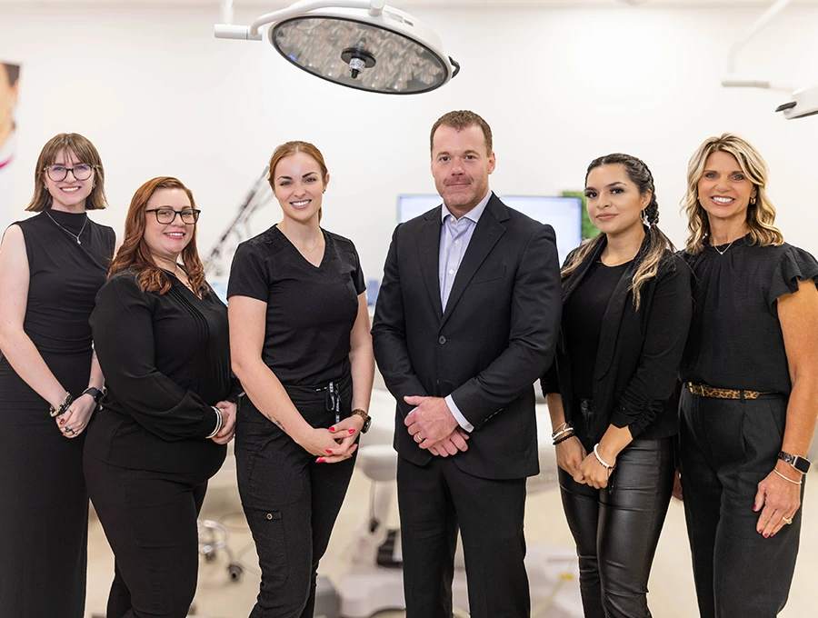 group of 5 women and 1 man posing in a line all wearing black