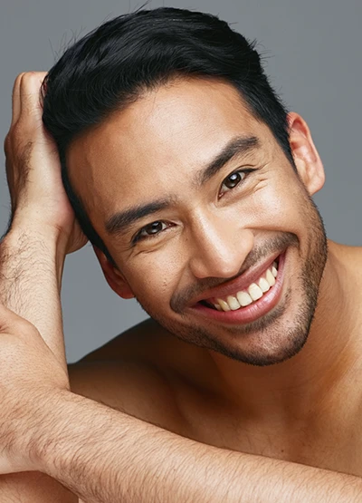 man with dark hair smiling on dark gray background